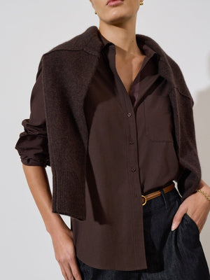 Buttoned shirt for women styled in dark brown with front pocket, soft collar, and a layered knit sweater over shoulders.