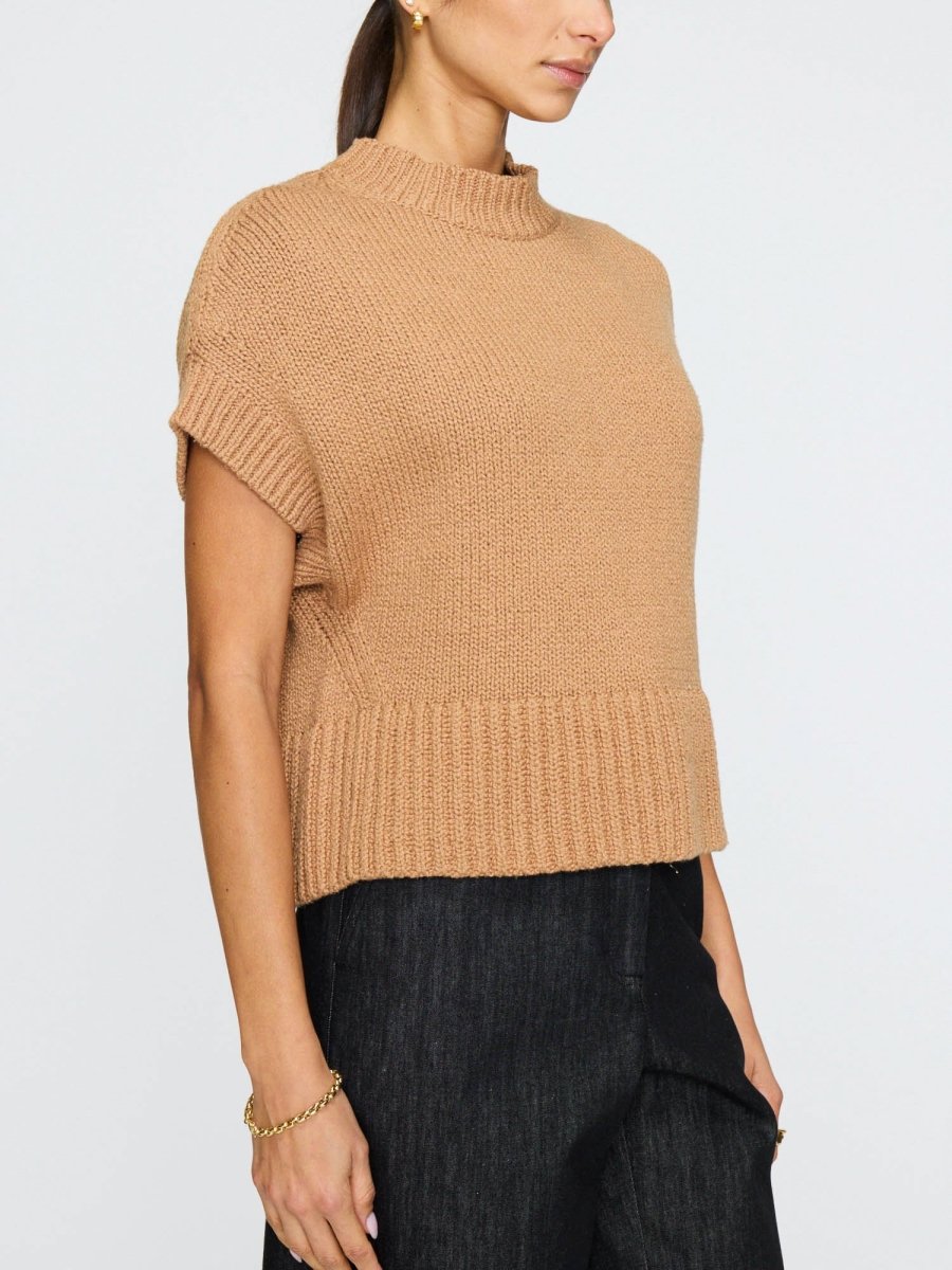 Women's sleeveless sweater in oatmeal beige with a soft drape, high neckline, and center seam detail down the back.