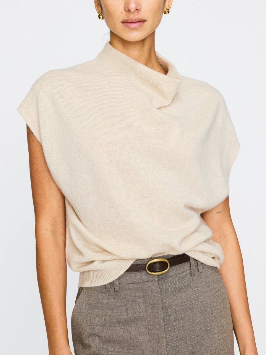 Cashmere top for women with a slightly asymmetric neckline and capped sleeves, tucked into high-waisted grey trousers with a belt.