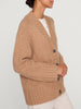 Women's camel cardigan with chunky knit texture, oversized fit, and dark buttons paired with light trousers.