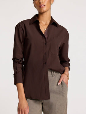 Women’s brown button-up shirt in soft cotton with chest pocket and casual collar, styled tucked into taupe trousers