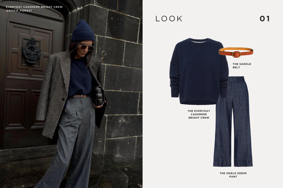 Sophisticated winter layering with a navy cashmere sweater, gray wide-leg trousers, a tweed overcoat, and a beanie for a timeless cold-weather look.