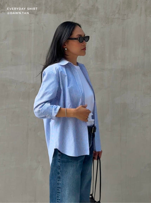 Casual chic outfit featuring the Everyday Shirt in blue stripes, styled with a white tee, denim, and sunglasses for a modern, laid-back look.