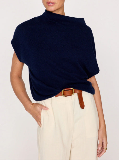 Navy funnel neck sweater cinched with a brown leather belt, paired with cream trousers, creating a polished and structured silhouette.