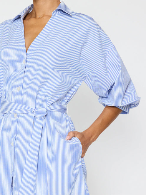 Close-up of a blue striped belted shirt dress, highlighting its crisp collar, voluminous sleeves, and flattering waist tie for a refined silhouette.